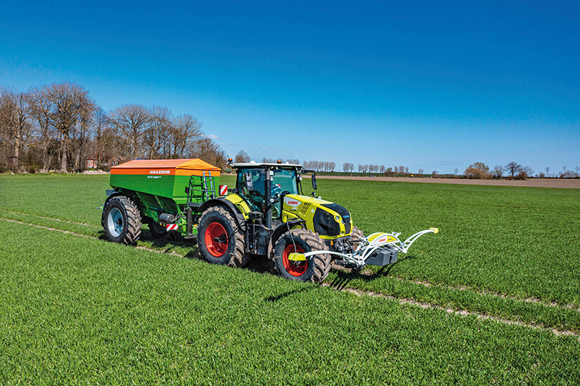 CLAAS-traktori vetää perässään Amazone XG-TX-kalkinlevytyslaitetta.