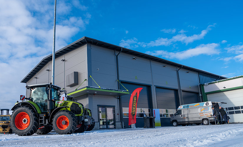 Hankkijan huollon uudet tilat, edessä CLAAS traktori, taustalla uusi huoltohalli ja sininen taivas