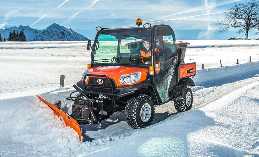 Kubota RTV X1110 lava-auto puskee lunta jossain pahuksen vuoristomaisemassa, jonka voisi melkein kuvitella Suomeksi.