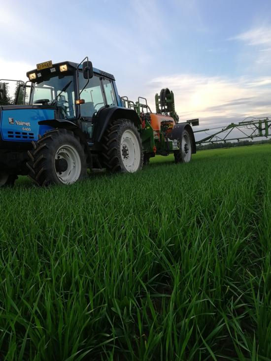 Traktori ja kasvinsuojeluruiskuruisku pellolla