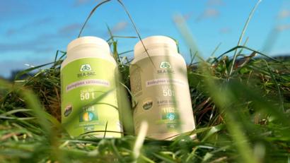 Kaksi Sila-Bac-säilöntäainepurkkia nurmella, etualalla vihreää ruohoa ja taustalla taivasta.